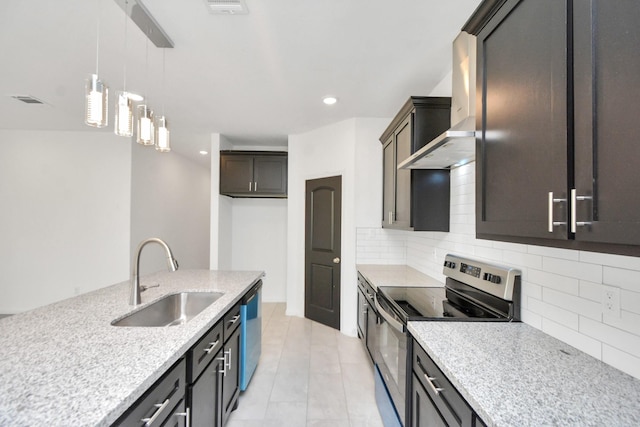 kitchen featuring pendant lighting, decorative backsplash, appliances with stainless steel finishes, wall chimney exhaust hood, and a sink