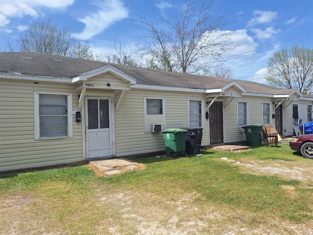 back of property with a yard and roof with shingles