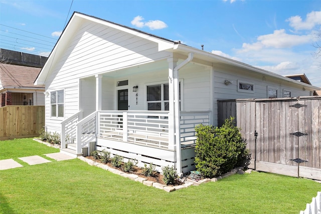 view of front facade featuring a porch, a front lawn, and fence