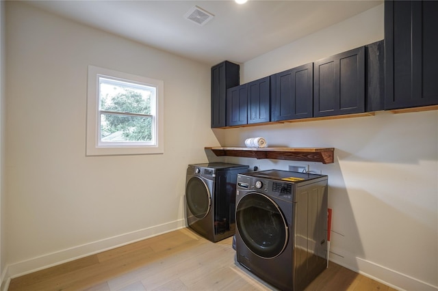 laundry room with cabinet space, visible vents, light wood-style floors, and washer and dryer