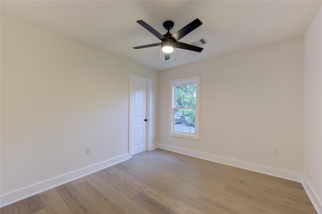 empty room with baseboards, a ceiling fan, visible vents, and light wood-style floors