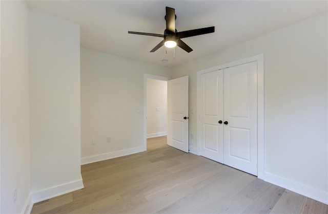 unfurnished bedroom featuring a ceiling fan, a closet, light wood-style flooring, and baseboards