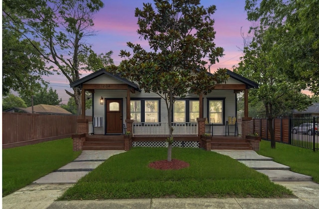 view of front of home featuring a front yard, covered porch, and fence