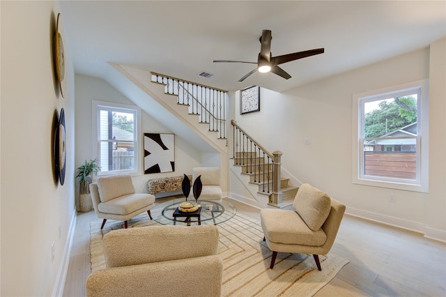 living area featuring wood finished floors, visible vents, baseboards, and stairs