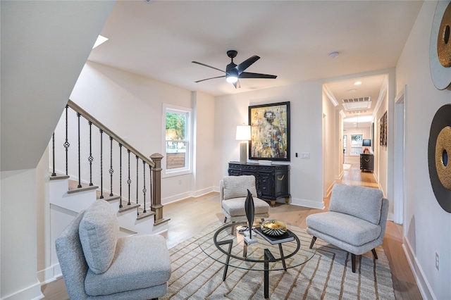 living area with stairs, ceiling fan, baseboards, and wood finished floors