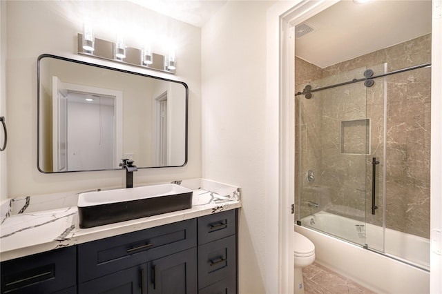 full bath featuring visible vents, vanity, toilet, and bath / shower combo with glass door