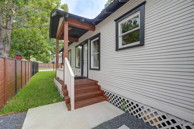 doorway to property with fence and a lawn