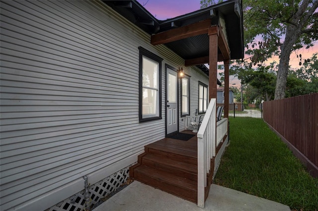 property exterior at dusk with a yard and fence