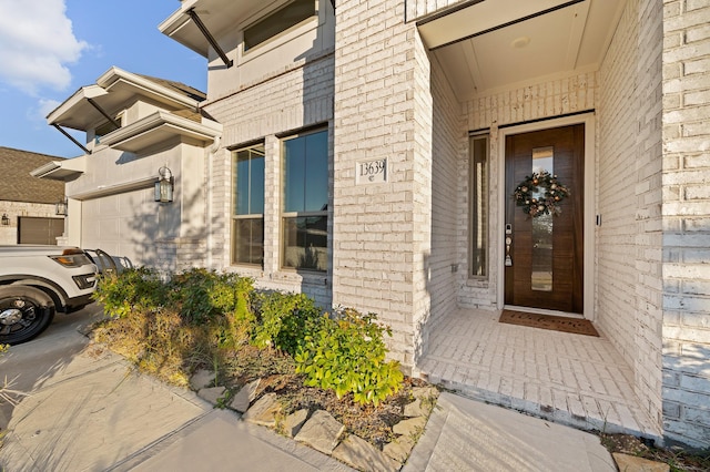 view of exterior entry featuring brick siding and an attached garage