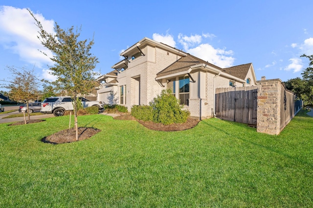 view of side of property featuring fence, a lawn, and brick siding