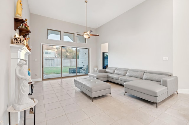 living area with light tile patterned floors, a ceiling fan, a towering ceiling, and baseboards