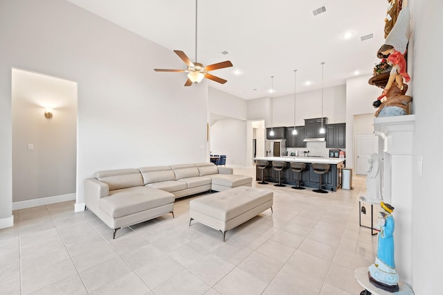 living room with ceiling fan, light tile patterned flooring, a towering ceiling, and visible vents