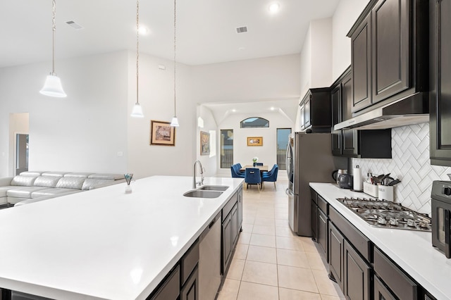 kitchen with stainless steel appliances, open floor plan, a sink, and light countertops