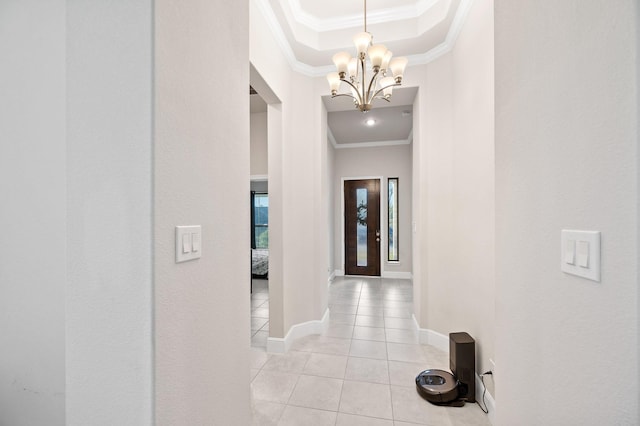 hall with baseboards, ornamental molding, a tray ceiling, a notable chandelier, and light tile patterned flooring