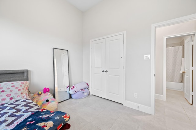 bedroom with light tile patterned floors, a closet, a towering ceiling, and baseboards