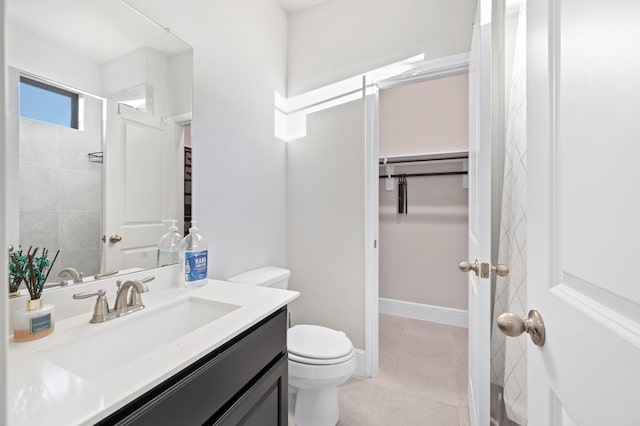 full bath featuring tile patterned flooring, toilet, vanity, baseboards, and a spacious closet