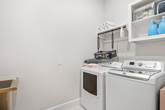 washroom with laundry area, separate washer and dryer, and baseboards