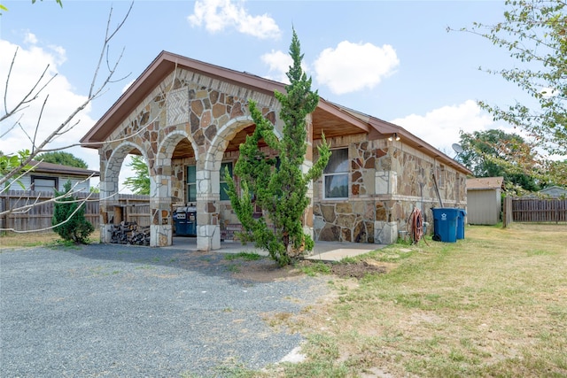 view of front of house with stone siding, a front lawn, and fence