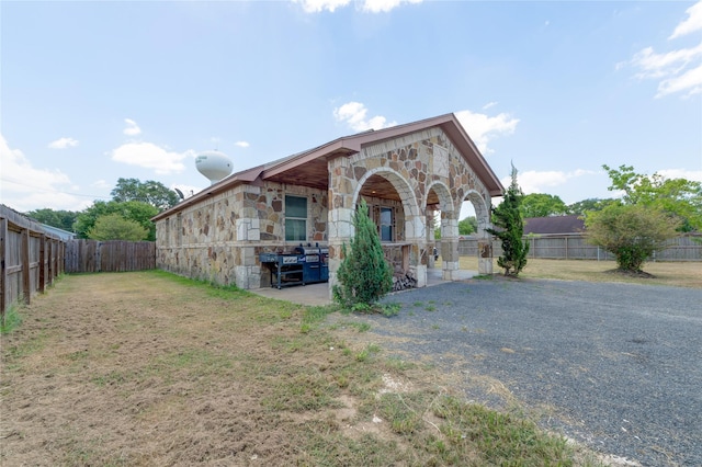 view of front of house featuring stone siding, a front yard, and a fenced backyard