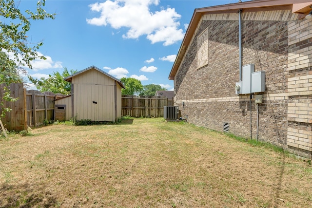 view of yard featuring central air condition unit, a shed, a fenced backyard, and an outbuilding