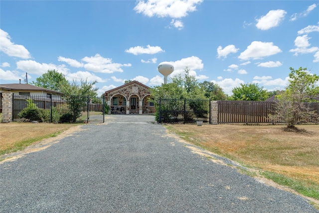 view of street with driveway, a gate, and a gated entry