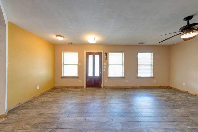 entrance foyer featuring ceiling fan, a textured ceiling, visible vents, and baseboards