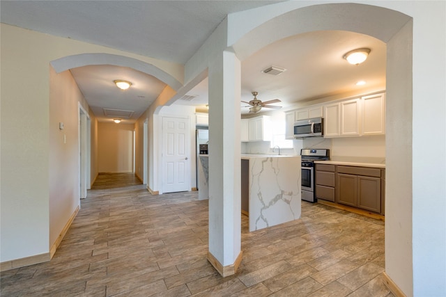 kitchen with stainless steel appliances, arched walkways, and light wood-style floors