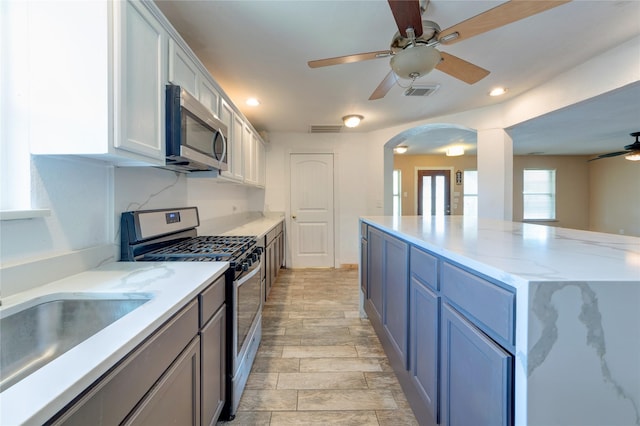 kitchen featuring arched walkways, a sink, visible vents, a ceiling fan, and appliances with stainless steel finishes