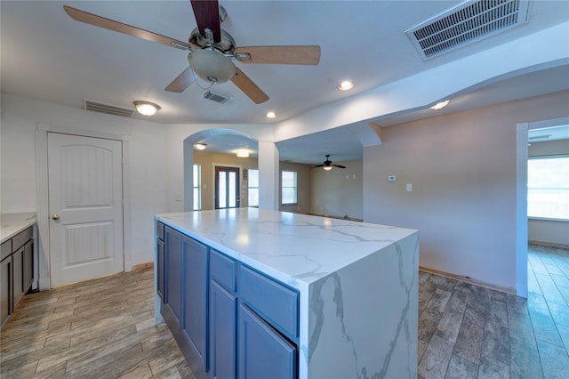 kitchen with light wood-type flooring, visible vents, and arched walkways