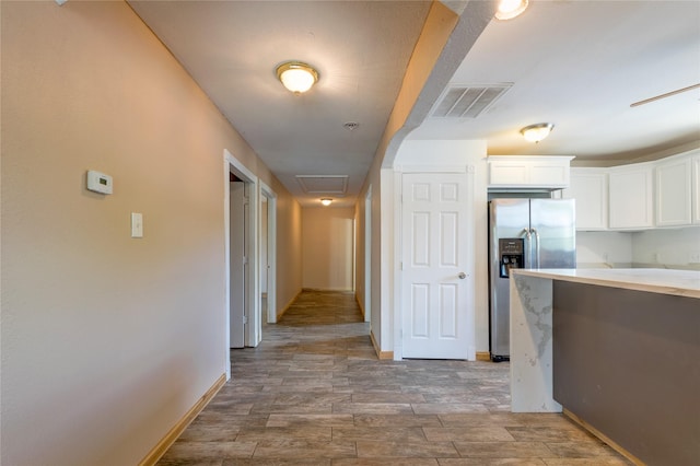 hallway featuring wood finished floors, visible vents, and baseboards