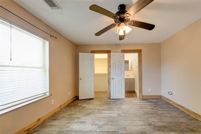 unfurnished bedroom with a walk in closet, visible vents, a ceiling fan, connected bathroom, and baseboards