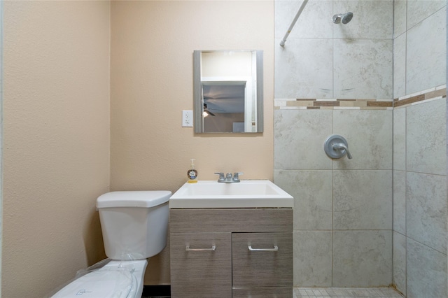 full bath with toilet, tiled shower, and vanity