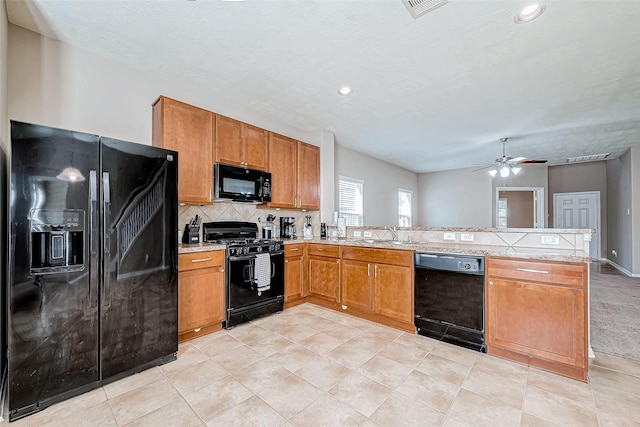 kitchen with a peninsula, light countertops, black appliances, tasteful backsplash, and brown cabinetry