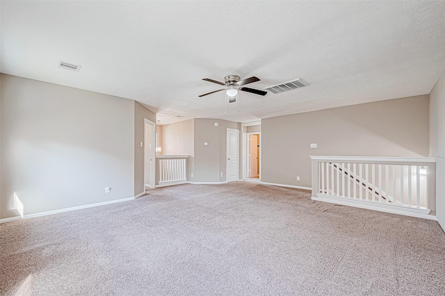 empty room featuring baseboards, visible vents, a textured ceiling, and light colored carpet