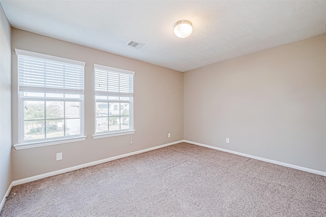 carpeted empty room with visible vents and baseboards