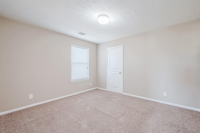 unfurnished room with baseboards, a textured ceiling, visible vents, and light colored carpet