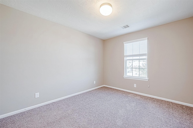 unfurnished room with carpet, baseboards, visible vents, and a textured ceiling