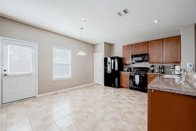 kitchen with a sink, visible vents, decorative backsplash, brown cabinets, and black appliances