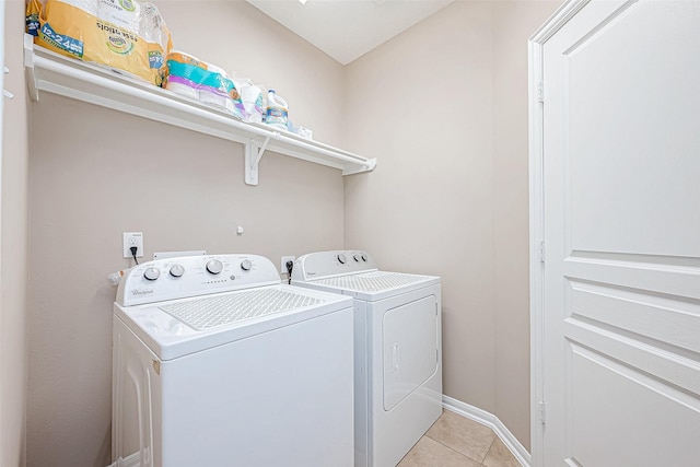 clothes washing area featuring laundry area, light tile patterned flooring, baseboards, and separate washer and dryer