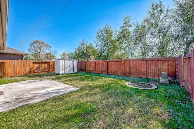 view of yard featuring a storage shed, a fenced backyard, a patio, and an outbuilding