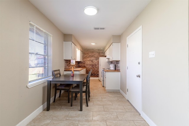 kitchen with visible vents, baseboards, light tile patterned flooring, white cabinets, and range