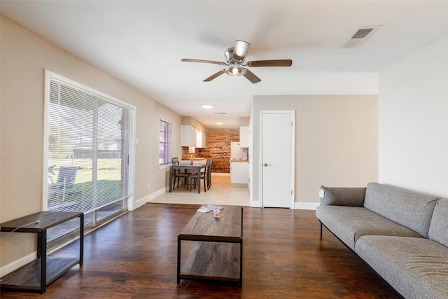 living area featuring visible vents, baseboards, a ceiling fan, and wood finished floors