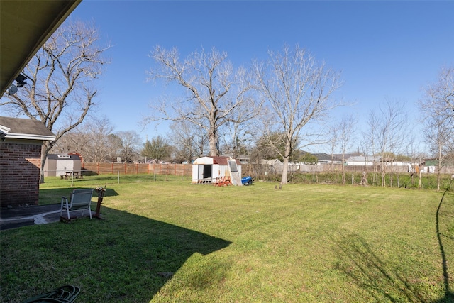 view of yard with an outdoor structure, a fenced backyard, and a shed