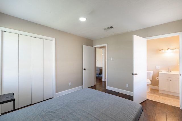 bedroom featuring baseboards, visible vents, ensuite bath, dark wood-style flooring, and a sink