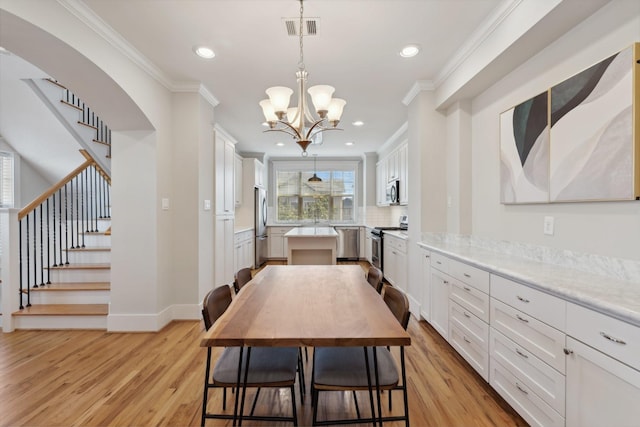 kitchen featuring a center island, visible vents, stainless steel appliances, and crown molding