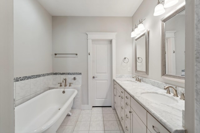 full bath featuring tile patterned floors, a freestanding tub, double vanity, and a sink