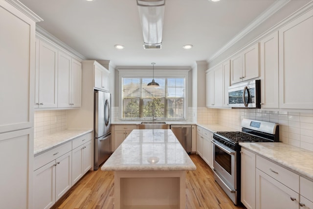 kitchen with a sink, light wood-style floors, appliances with stainless steel finishes, and white cabinetry