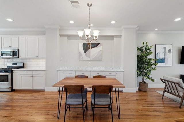 dining area featuring visible vents, baseboards, light wood-style flooring, and a chandelier