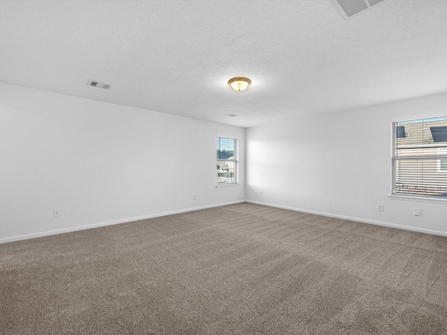 carpeted spare room featuring visible vents, baseboards, and a textured ceiling