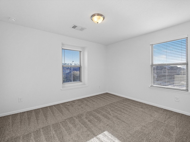 carpeted spare room with visible vents and baseboards